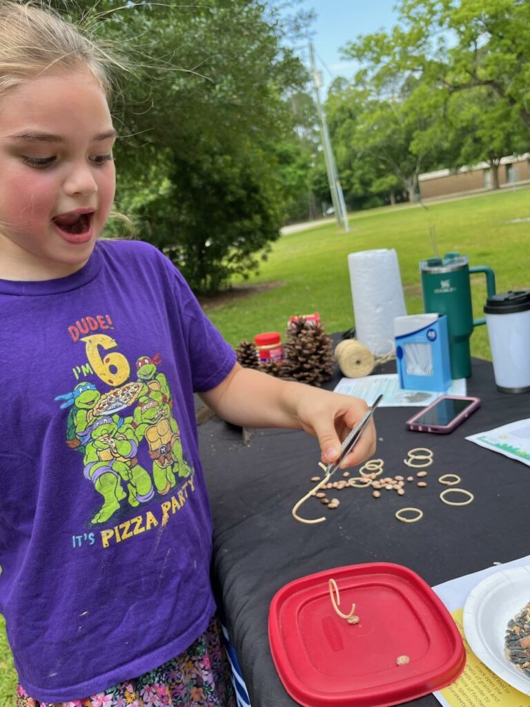 A girl picks up pasta "worms" to see how birds eat.